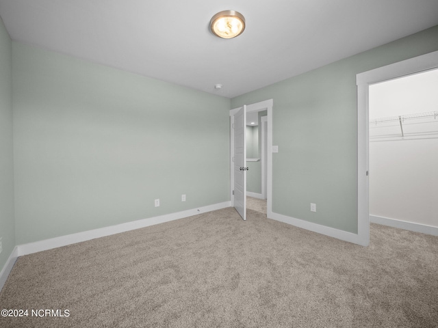 unfurnished bedroom featuring a closet, a spacious closet, and carpet flooring