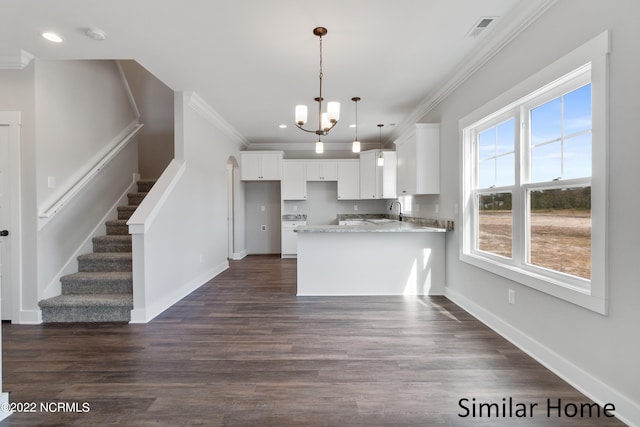 kitchen featuring kitchen peninsula, a notable chandelier, dark hardwood / wood-style floors, white cabinetry, and pendant lighting