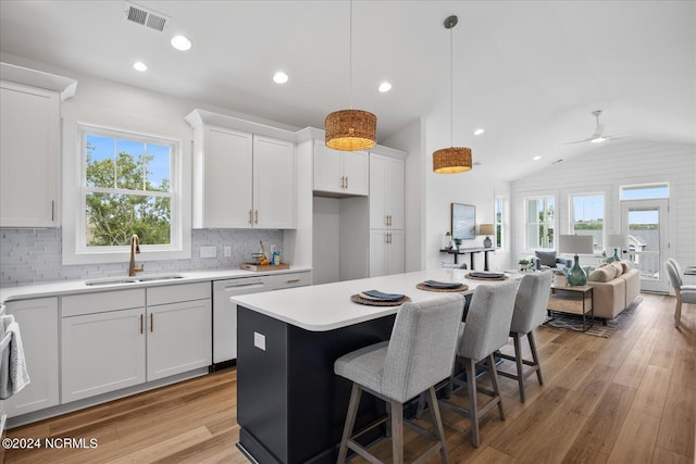 kitchen with white cabinetry, plenty of natural light, sink, and vaulted ceiling