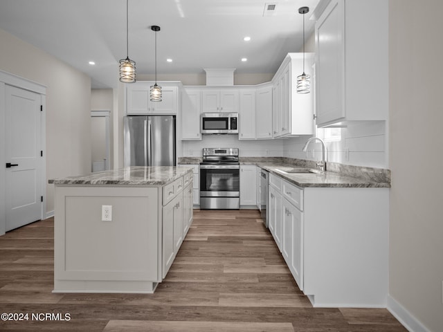 kitchen with sink, white cabinetry, stainless steel appliances, a center island, and decorative light fixtures