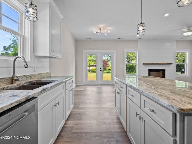 kitchen featuring sink, decorative light fixtures, light hardwood / wood-style flooring, stainless steel dishwasher, and white cabinets