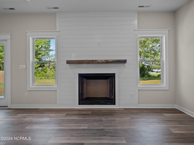 unfurnished living room with dark wood-type flooring, plenty of natural light, and a large fireplace