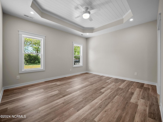 spare room with wood ceiling, crown molding, a raised ceiling, and light hardwood / wood-style floors