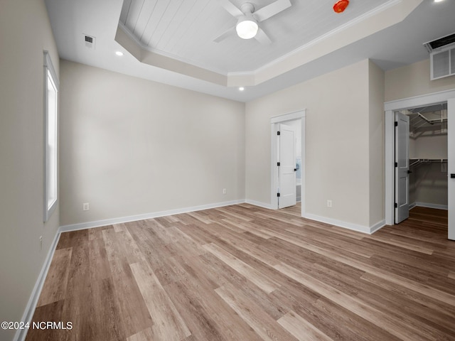 spare room with crown molding, ceiling fan, a tray ceiling, and light hardwood / wood-style floors