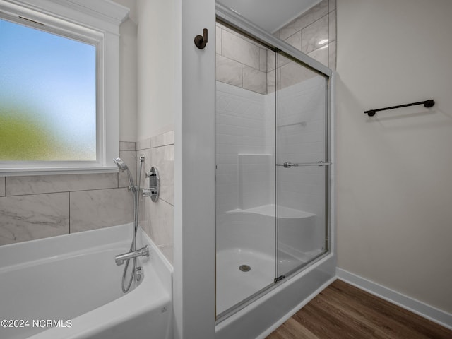 bathroom with wood-type flooring, plus walk in shower, and a healthy amount of sunlight