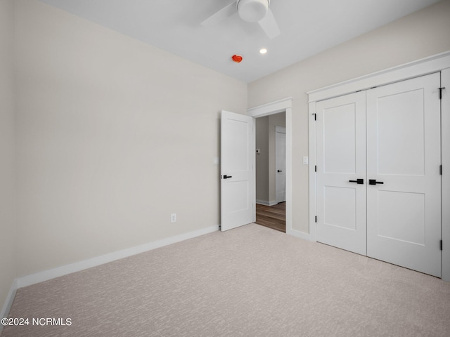 unfurnished bedroom with ceiling fan, light carpet, and a closet