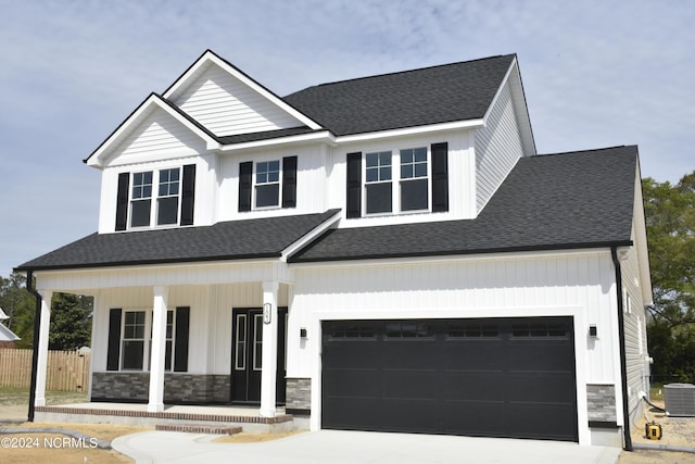 view of front facade featuring cooling unit, a garage, and covered porch