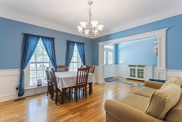 dining room with ornamental molding, light hardwood / wood-style floors, and a notable chandelier