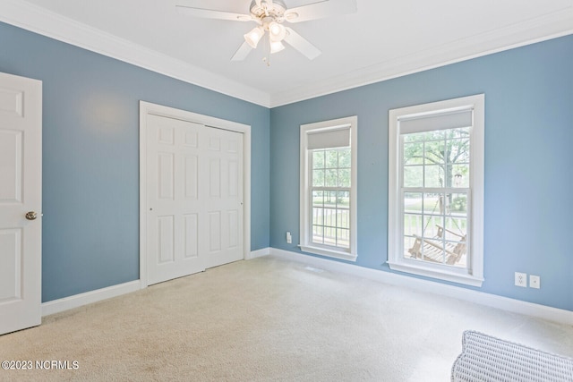 unfurnished bedroom with ceiling fan, crown molding, a closet, and light colored carpet