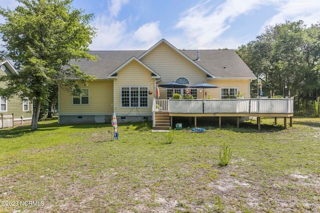 rear view of property featuring a wooden deck and a lawn