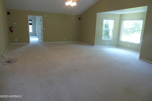 carpeted spare room featuring vaulted ceiling and ceiling fan