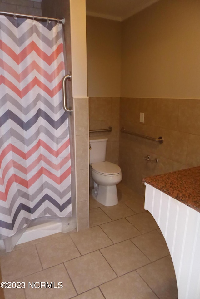 bathroom with tile floors, toilet, and tile walls