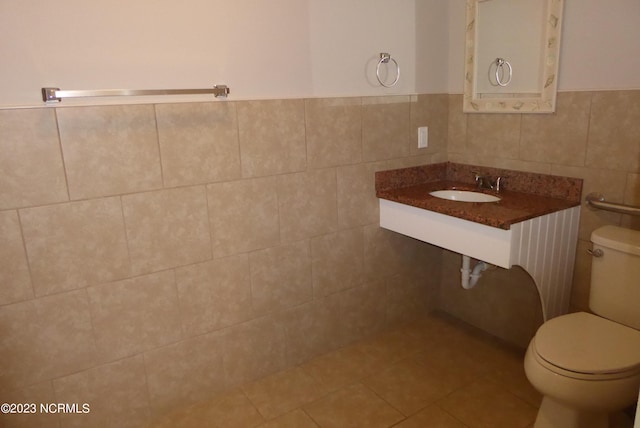 bathroom featuring tile flooring, tile walls, and toilet