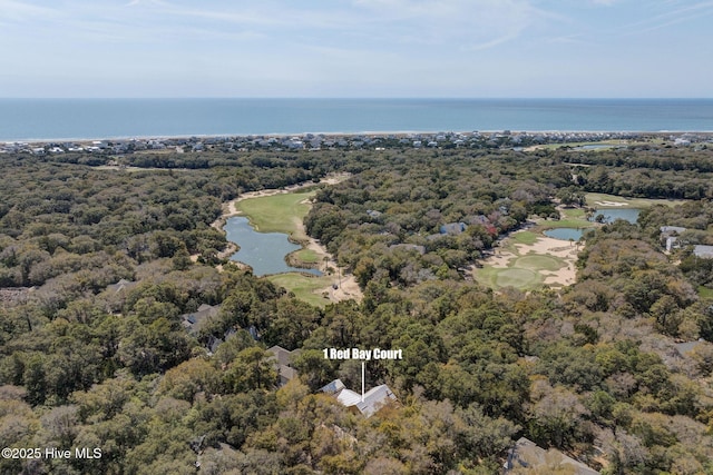 aerial view of property and surrounding area featuring a nearby body of water, a golf club, and a heavily wooded area