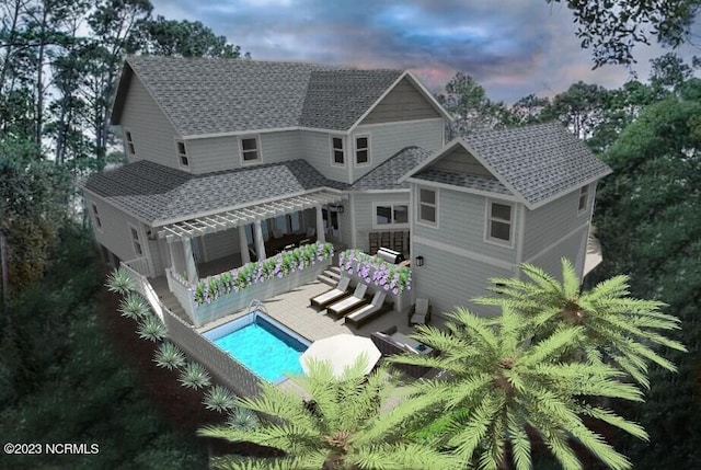 rear view of property featuring an outdoor pool and roof with shingles