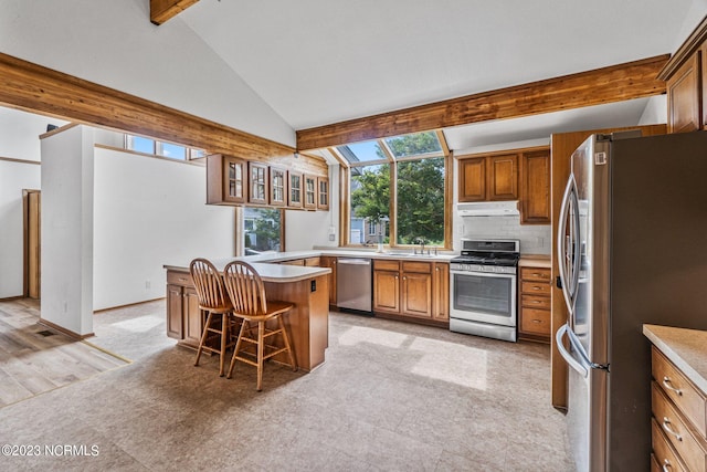 kitchen featuring lofted ceiling with beams, backsplash, a breakfast bar area, stainless steel appliances, and a center island