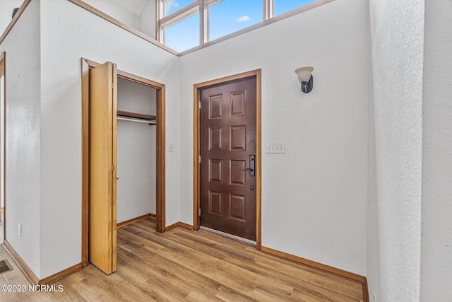 entryway featuring light hardwood / wood-style floors and a towering ceiling