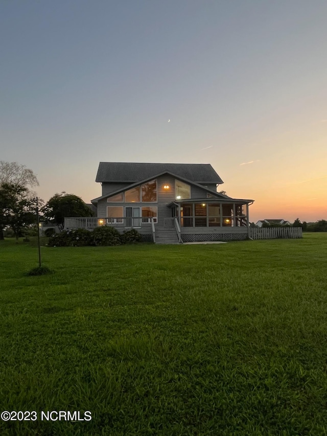 back house at dusk featuring a lawn