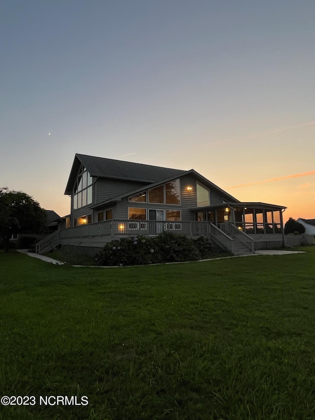 back house at dusk with a lawn