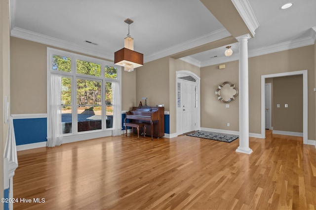 foyer entrance with decorative columns, light hardwood / wood-style floors, and ornamental molding