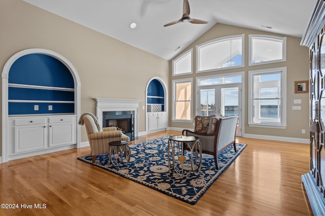 living room with light hardwood / wood-style floors, high vaulted ceiling, and ceiling fan