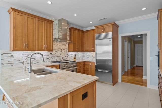 kitchen featuring kitchen peninsula, premium appliances, wall chimney exhaust hood, and sink