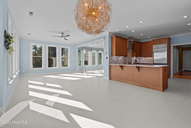 kitchen with tasteful backsplash, kitchen peninsula, a wealth of natural light, and stainless steel built in refrigerator