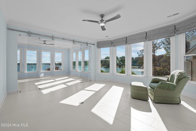 sunroom / solarium featuring ceiling fan and a water view