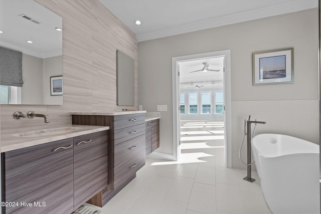 bathroom featuring a washtub, tile patterned floors, crown molding, vanity, and tile walls