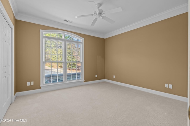 unfurnished room with light carpet, ceiling fan, and ornamental molding