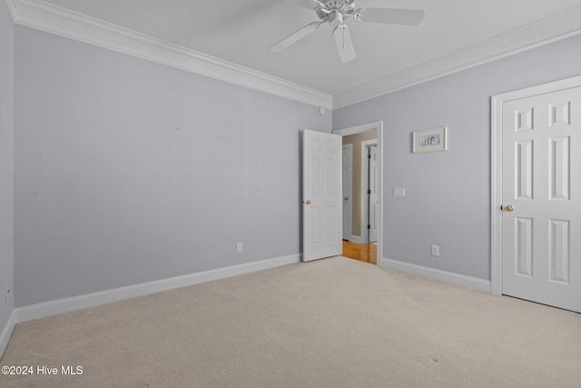 unfurnished bedroom featuring ceiling fan, crown molding, and light carpet