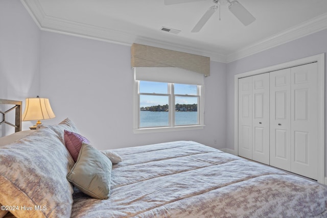 bedroom with ceiling fan, a closet, a water view, and ornamental molding