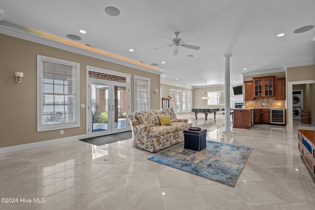 living room featuring french doors, crown molding, wine cooler, ceiling fan, and decorative columns