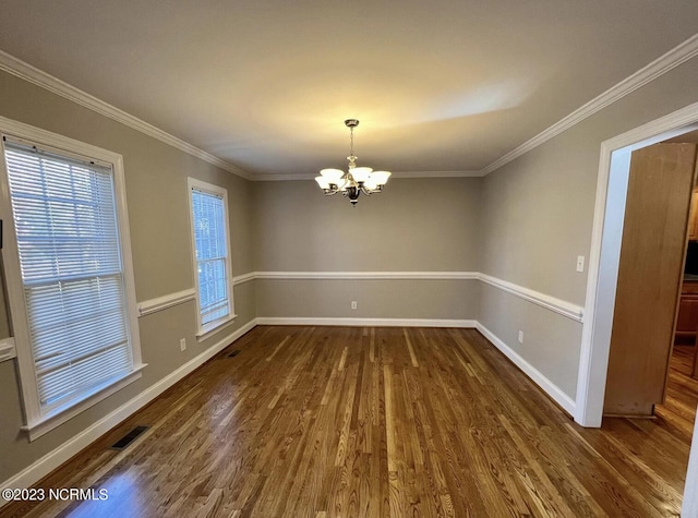 empty room featuring dark hardwood / wood-style flooring, an inviting chandelier, and crown molding