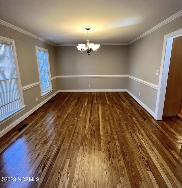 spare room featuring a notable chandelier, dark wood-type flooring, and ornamental molding