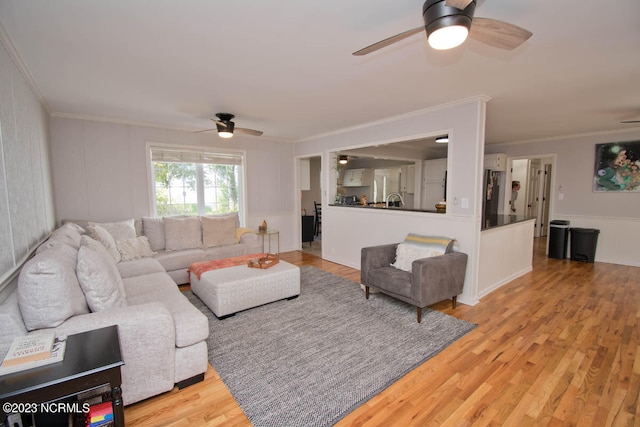 living room with ceiling fan, light wood-type flooring, and crown molding