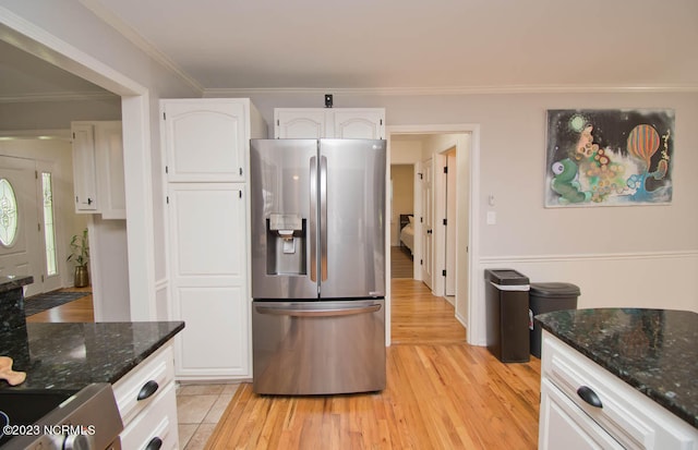 kitchen with light wood-type flooring, dark stone countertops, white cabinets, stainless steel refrigerator with ice dispenser, and ornamental molding