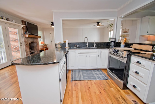 kitchen featuring light hardwood / wood-style flooring, a brick fireplace, and ceiling fan