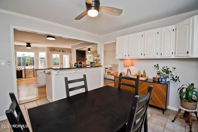 dining space featuring ceiling fan, crown molding, and light tile flooring