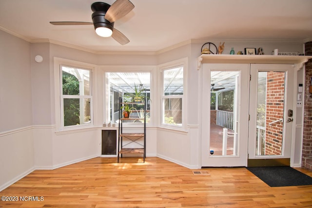 entryway featuring light wood-type flooring, ceiling fan, ornamental molding, and a healthy amount of sunlight