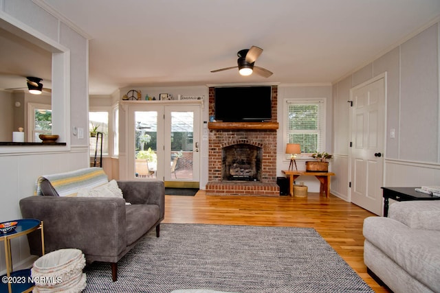 living room featuring ceiling fan, plenty of natural light, a fireplace, and light hardwood / wood-style floors