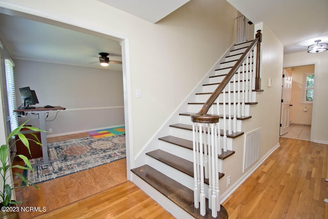 stairway featuring light hardwood / wood-style flooring, ceiling fan, and a healthy amount of sunlight