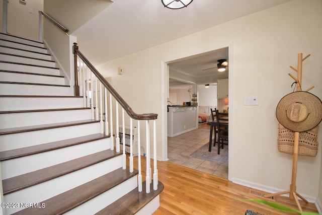 staircase with ceiling fan and light wood-type flooring