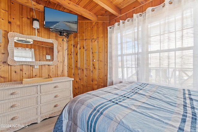 bedroom with beamed ceiling, light hardwood / wood-style floors, wooden walls, and wooden ceiling