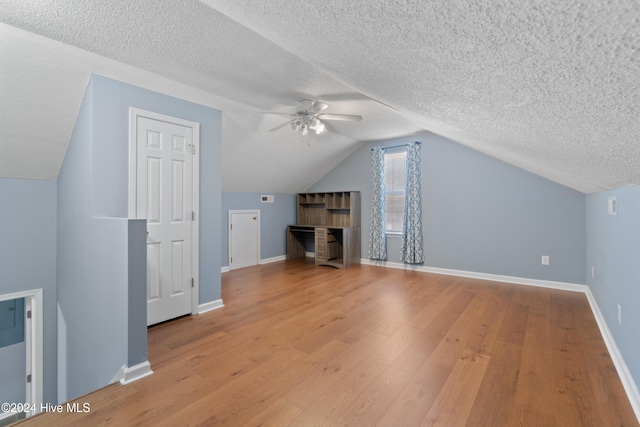 bonus room featuring a textured ceiling, light hardwood / wood-style flooring, and lofted ceiling