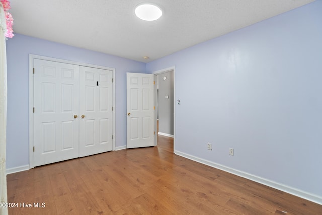 unfurnished bedroom with a closet, a textured ceiling, and hardwood / wood-style flooring