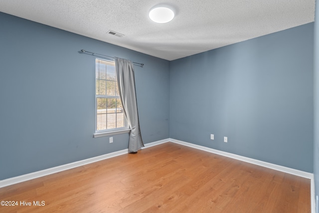 spare room with a textured ceiling and hardwood / wood-style flooring