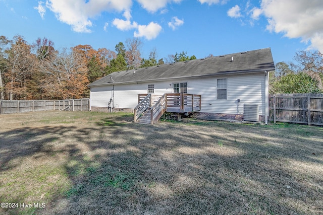 rear view of property featuring a lawn, cooling unit, and a deck