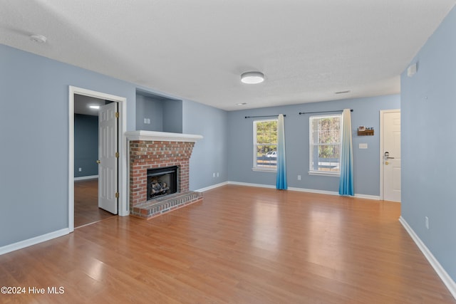 unfurnished living room with a fireplace, a textured ceiling, and light wood-type flooring