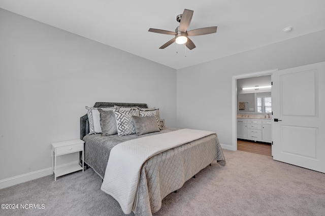 bedroom with ceiling fan, ensuite bathroom, and light carpet